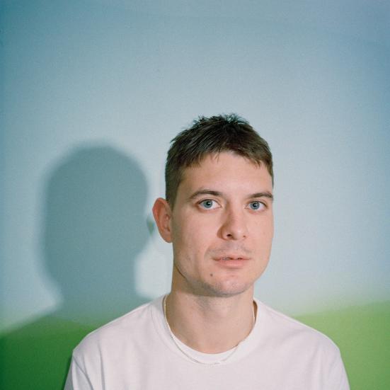 Portræt af Caspar Eric i en hvid tshirt foran en neutral baggrund