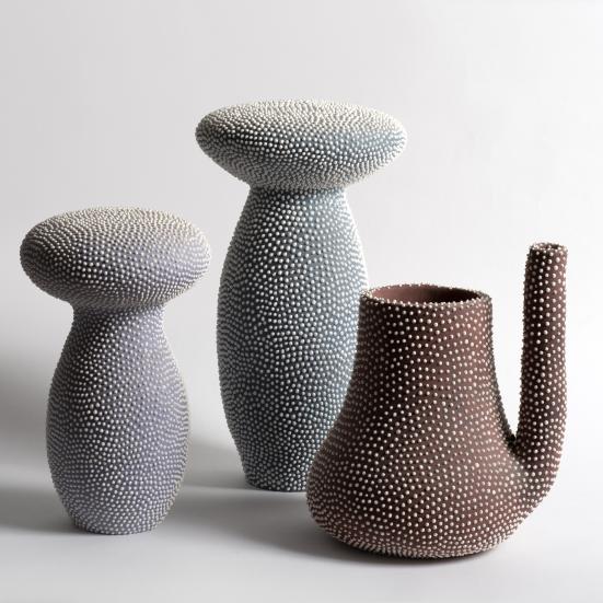 to svampelignende keramiske figurer og en kande ses mod en enkel hvid baggrund