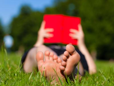 mand læser bog i græsset