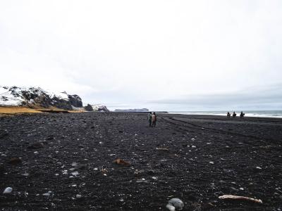 barskt landskab med bjerge, sort strand og vand