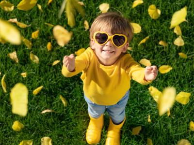 Barn med hjertesolbriller rækker ud efter efterårsblade