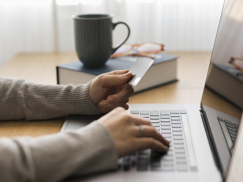 Hænder på computertastatur. kop og bog i baggrunden